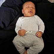 Zymir is registered to the contest to win money with this photo: baby, sleeping, infant, white_clothing, gray_pants, blanket, mattress, peaceful, hands, feet, face, portrait, indoor, rest, child, cozy, cute, relaxation, person, sleep