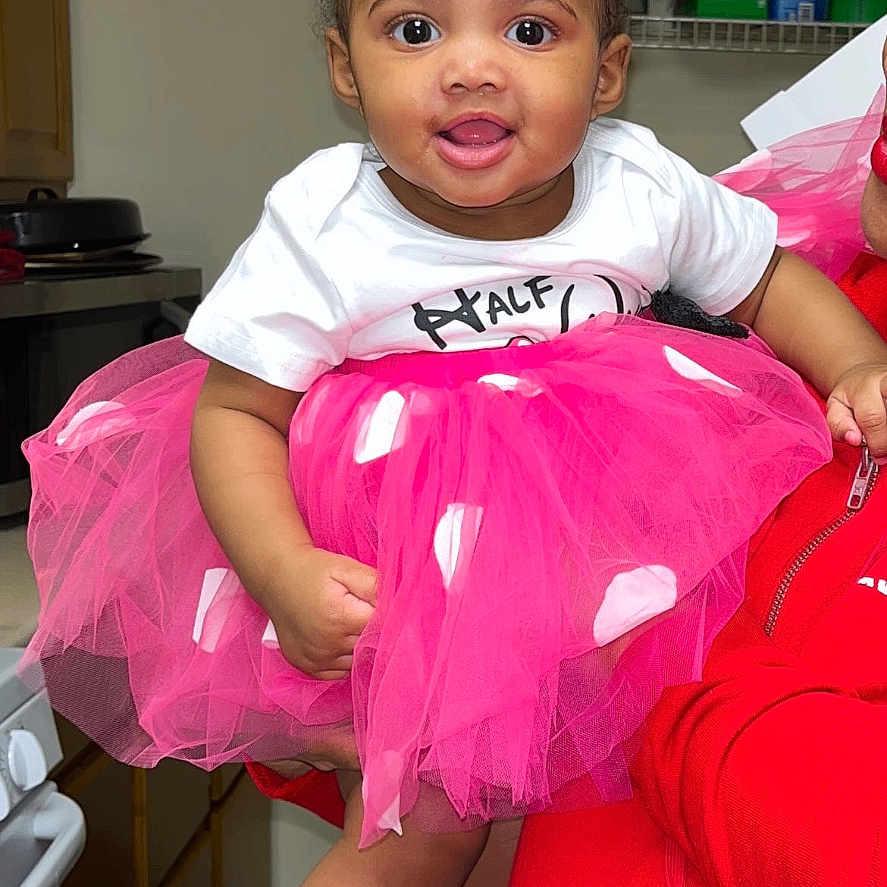 Azuri is registered to the contest to win money with this photo: accessories, baby, bodypart, clothing, costume, dress, face, furniture, hat, head, indoors, jewelry, mouth, person, photography, portrait, purple, skirt, t_shirt, teeth