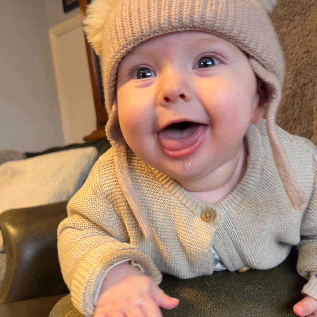 Hunter joined the competition — help win amazing prizes! armrest, baby, chair, child, cozy, cute, drool, furniture, happy, hat, home, indoor, infant, knit_hat, leather, person, pom_poms, portrait, smiling, sweater