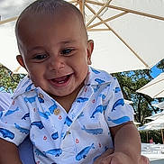 Romeo Jr is registered to the contest to win money with this photo: baby, child, smiling, happy, outdoor, umbrella, shirt, whale_pattern, person, hand, trees, daylight, sunny, nature, family, holding, blue_sky, casual_clothing, infant, cheerful