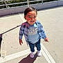 child, toddler, boy, outdoor, sunny, plaid_shirt, blue_tshirt, best_brother, jeans, white_sneakers, smiling, shadow, concrete, parking_lot, railing, plants, daylight, casual_clothing, happy, standing