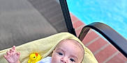 Austin joined the competition — help win amazing prizes! baby, child, towel, poolside, chair, rubber_duck, white_shirt, blue_shorts, bracelet, outdoor, daylight, water, pool, relaxing, person, infant, cute, summer, toy, skin