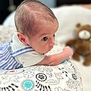 Austin joined the competition — help win amazing prizes! baby, infant, face, eyes, cushion, pattern, striped_clothing, teddy_bear, toy, bed, white_background, soft_toy, child, cute, indoors, portrait, lying_down, close_up, young_child, curious