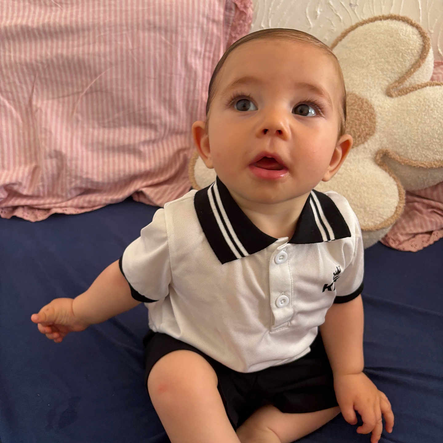 Raïdenn participe au concours pour gagner de l'argent avec cette photo : baby, child, clothing, curious, cushion, expression, fabric, flower_shape, foot, hand, indoor, infant, pillow, polo_shirt, portrait, shorts, sitting, skin, textured_wall, wall