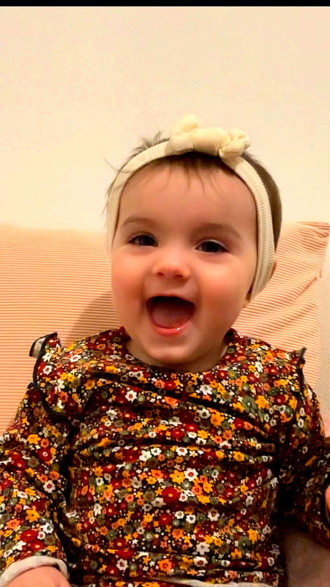 Lëannah a rejoint le concours — aidez-le/la à gagner de superbes lots ! baby, background, cheerful, child, clothing, cute, expression, face, flower_pattern, happy, headband, headwear, indoors, infant, person, portrait, sitting, smiling, warm_colors, young_child