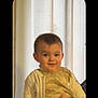 Lëannah a rejoint le concours — aidez-le/la à gagner de superbes lots ! toddler, child, smiling, golden_clothing, cardigan, portrait, indoor, curtain, cute, happy, baby, face, person, young_child, fashion, seated, light, expression, cozy, warm