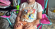 Lucy joined the competition — help win amazing prizes! carpet, chair, child, cute, footwear, furniture, happy, indoor, kid, living_room, person, pink, room, shorts, sitting, smiling, television, toy, tshirt, turquoise