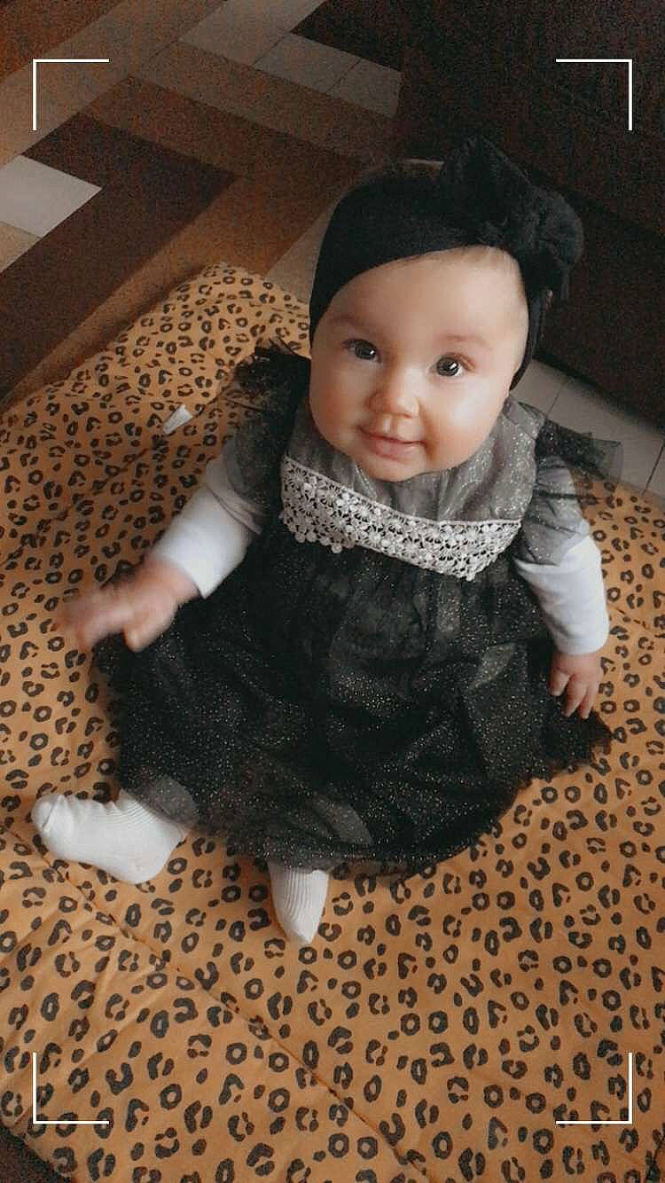 Kiara a rejoint le concours — aidez-le/la à gagner de superbes lots ! baby, baby_toddler_clothing, cheek, doll, floor, flooring, fur, hardwood, head, headwear, iris, pattern, person, sitting, skin, sleeve, smile, toddler, toy, wood