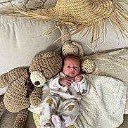 Melynda a rejoint le concours — aidez-le/la à gagner de superbes lots ! baby, infant, newborn, plush_toy, teddy_bear, crochet_toy, straw_hat, sofa, blanket, cushion, woven_basket, heart_pajamas, lying_down, cute, portrait, home_interior, hand, eyes_open, cozy, soft_textures