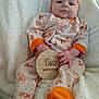 Octavia is registered to the contest to win money with this photo: baby, infant, pajamas, orange, white, blanket, sign, wooden_sign, two_months, cute, child, portrait, indoor, soft_texture, smile, headband, hands, feet, cozy, sitting