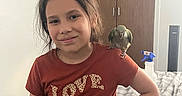 Ariel Rose is registered to the contest to win money with this photo: child, girl, parrot, bird, pet, shoulder, tshirt, love_text, bedroom, bed, blanket, spray_bottle, wooden_closet, smile, hair, person, indoor, casual, standing, hand_on_hip