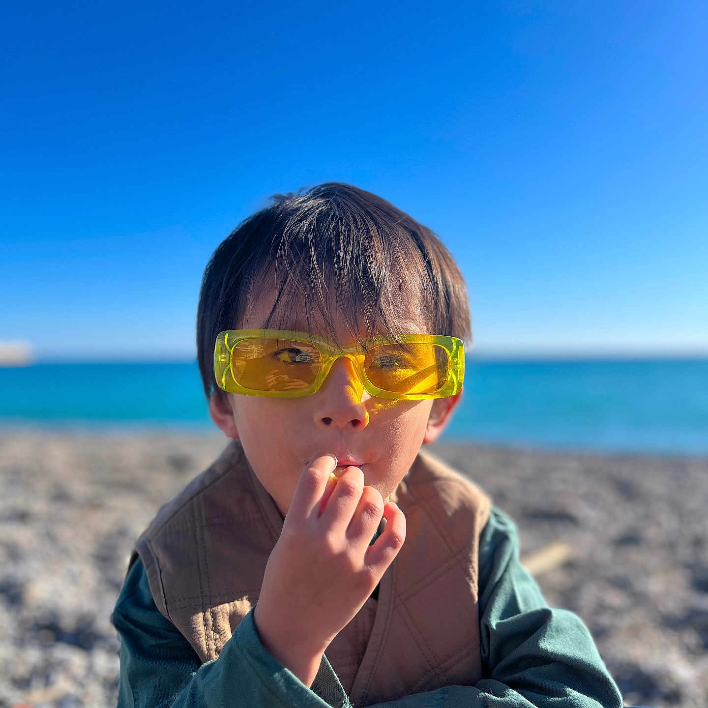 Loden participe au concours pour gagner de l'argent avec cette photo : accessories, baby, beach, bodypart, clothing, coast, coat, face, finger, hand, head, nature, outdoors, person, photography, portrait, sea, shoreline, sunglasses, water