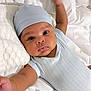 baby, infant, sleepwear, hat, arm, bed, pillow, pacifier, white, blue, cute, lying_down, child, bracelet, knitted, soft, peaceful, indoors, portrait, closeup
