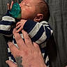 newborn, baby, sleeping, pacifier, striped_clothing, hand, tattoo, skin, infant, child, person, resting, closeup, indoors, portrait, peaceful, soft_lighting, blanket, comfort, toddler