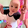Cylas is registered to the contest to win money with this photo: baby, black_and_white, blurred_background, candid, child, clothing, curious, expression, face, family, hands, happy, holding_hands, indoor, person, pink, playing, standing, toys, young_child