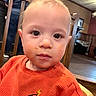 Cylas is registered to the contest to win money with this photo: baby, blurred_background, casual, child, clothing, cute, expressionless, eyelashes, face, food, high_chair, home, indoor, light, messy, orange_sweater, person, portrait, wooden_furniture, young_child