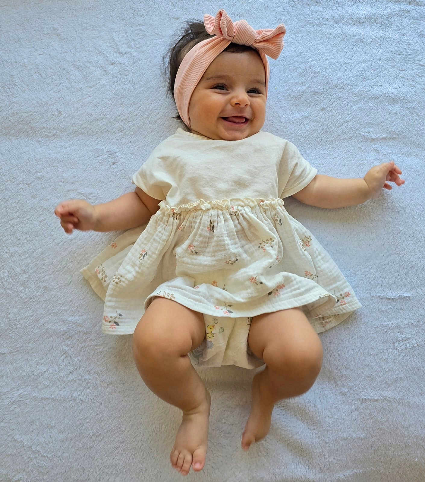 Inna a rejoint le concours — aidez-le/la à gagner de superbes lots ! baby, smiling, headband, pink_bow, dress, floral_pattern, barefoot, lying_down, happy, infant, cute, child, soft_blanket, indoors, adorable, portrait, skin, person, toddler, clothing
