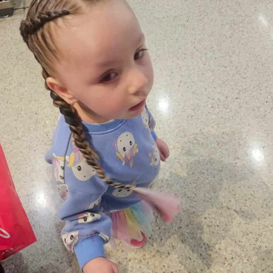 Mia joined the competition — help win amazing prizes! blue_sweater, braids, casual_wear, child, colorful_skirt, curious, cute, floor, floor_tiles, hair_style, holding_hand, indoor, long_braids, looking_up, patterned_clothing, person, playful, shadow, standing, young_child