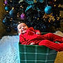 Rebel is registered to the contest to win money with this photo: baby, carpet, celebration, child, christmas_tree, cozy, cute, decorations, festive, green_box, holiday, indoor, infant, joyful, lights, ornaments, plaid, red_onesie, smile, smiling