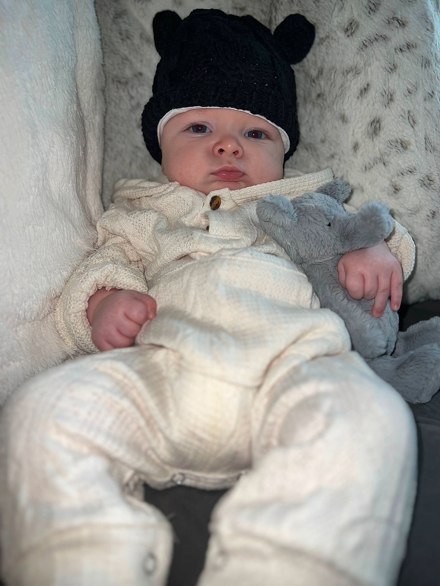 Jaxon is registered to the contest to win money with this photo: baby, baby_toddler_clothing, beanie, cap, cheek, child, collar, comfort, eye, face, fur, headgear, headwear, human_body, knit_cap, pattern, person, sitting, sleeve, toddler