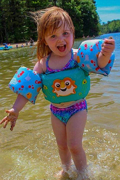 Stella is registered to the contest to win money with this photo: baby_toddler_clothing, beach, child, fun, happy, lake, leisure, maillot, one_piece_swimsuit, person, personal_protective_equipment, pink, recreation, sky, sleeve, smile, summer, swimwear, toddler, tree