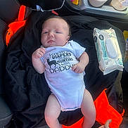 Draven is registered to the contest to win money with this photo: awake, baby, baby_wipes, blue_eyes, car_interior, car_seat, child, clothing, drinks, family, hands, indoor, infant, lying_down, orange_fabric, photography, portrait, smiling, vehicle, white_onesie