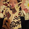 Willow is registered to the contest to win money with this photo: baby, infant, child, portrait, face, eyes, tongue, blanket, hood, onesie, sleepwear, cozy, lying_down, indoor, pink_background, textile, foot, hand, patterned, photography