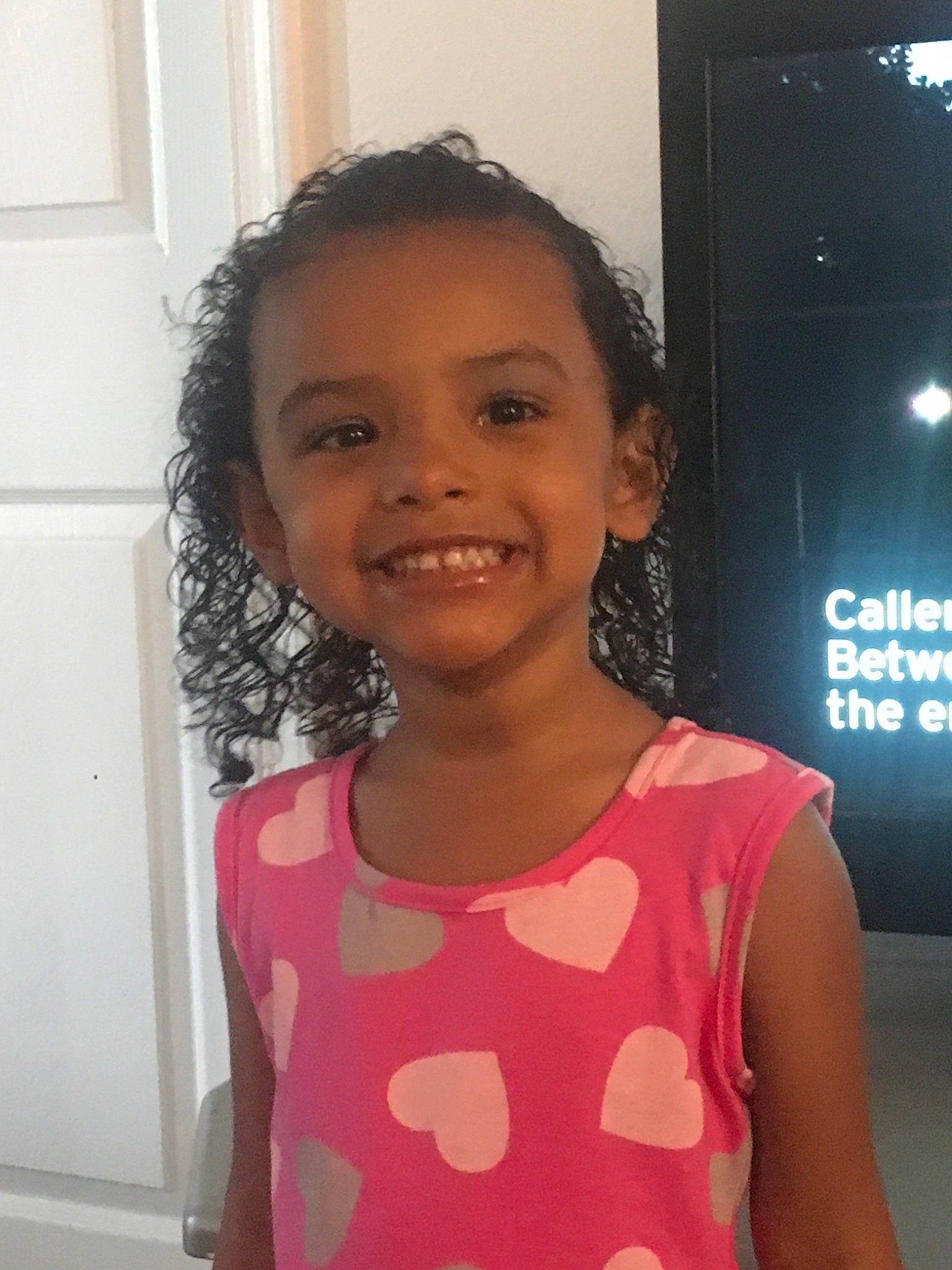 Gabby is registered to the contest to win money with this photo: black_hair, child, daughter, face, forehead, fun, hair, hairstyle, happy, head, joy, long_hair, neck, person, pink, shoulder, skin, smile, t_shirt, toddler