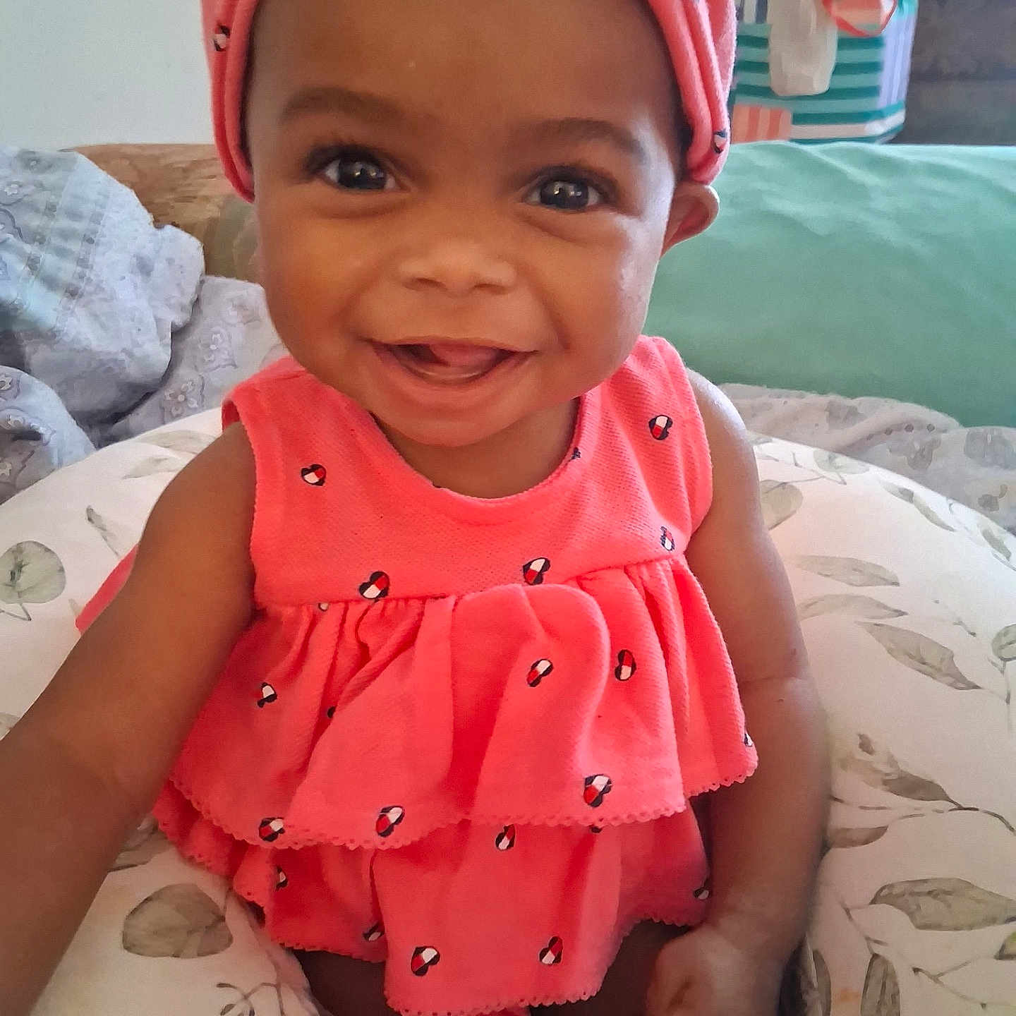 Kimora joined the competition — help win amazing prizes! baby, child, smiling, pink_clothing, headwrap, sitting, cushion, indoor, portrait, happy, face, cute, infant, home, person, bright_colors, closeup, expression, toddler, joy