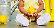 Kimora joined the competition — help win amazing prizes! baby, child, yellow_clothing, headband, lemon, rain_boots, watering_can, flowers, floor, indoor, gown, white_shoes, gingham_cloth, cute, portrait, sitting, bright_colors, happy, expression, studio