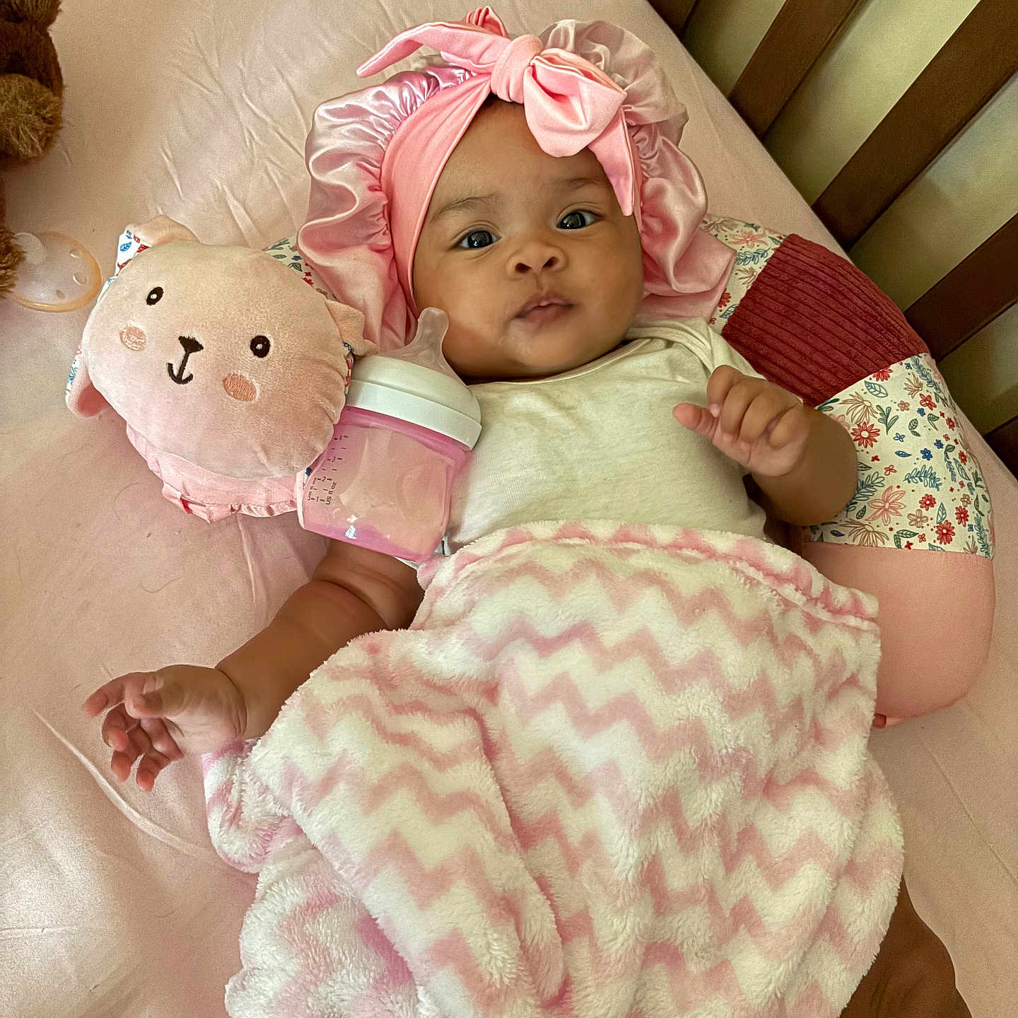 Zariyah joined the competition — help win amazing prizes! baby, child, infant, crib, pink_bow, headband, blanket, plush_toy, bunny, baby_bottle, bed, pillow, lying_down, indoors, portrait, smiling, awake, cozy, nursery, photography