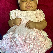 Lailani Anaisa is registered to the contest to win money with this photo: baby, child, pink_dress, headband, smile, roses, frilly, cute, infant, cheeks, fabric, clothing, portrait, lying_down, adorable, happy, toddler, hands, background, red