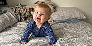 Mylo-Jay joined the competition — help win amazing prizes! baby, infant, child, crawling, bed, bedding, blanket, pillow, blue_clothing, dinosaur_print, smiling, happy, indoor, home, person, cute, face, head, expression, cozy