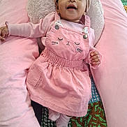 Prescious is registered to the contest to win money with this photo: baby, child, pink_clothing, headwrap, smiling, cushion, soft_texture, cute, infant, relaxing, indoors, happy, face, sock, patterned_blanket, portrait, cozy, cute_outfit, baby_girl, comfortable