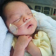 Danessica is registered to the contest to win money with this photo: newborn, baby, sleeping, blanket, nasal_cannula, oxygen_tube, tape, infant, clothing, yellow_outfit, hand, face, closed_eyes, resting, car_seat, soft_texture, skin, healthcare, peaceful, indoors