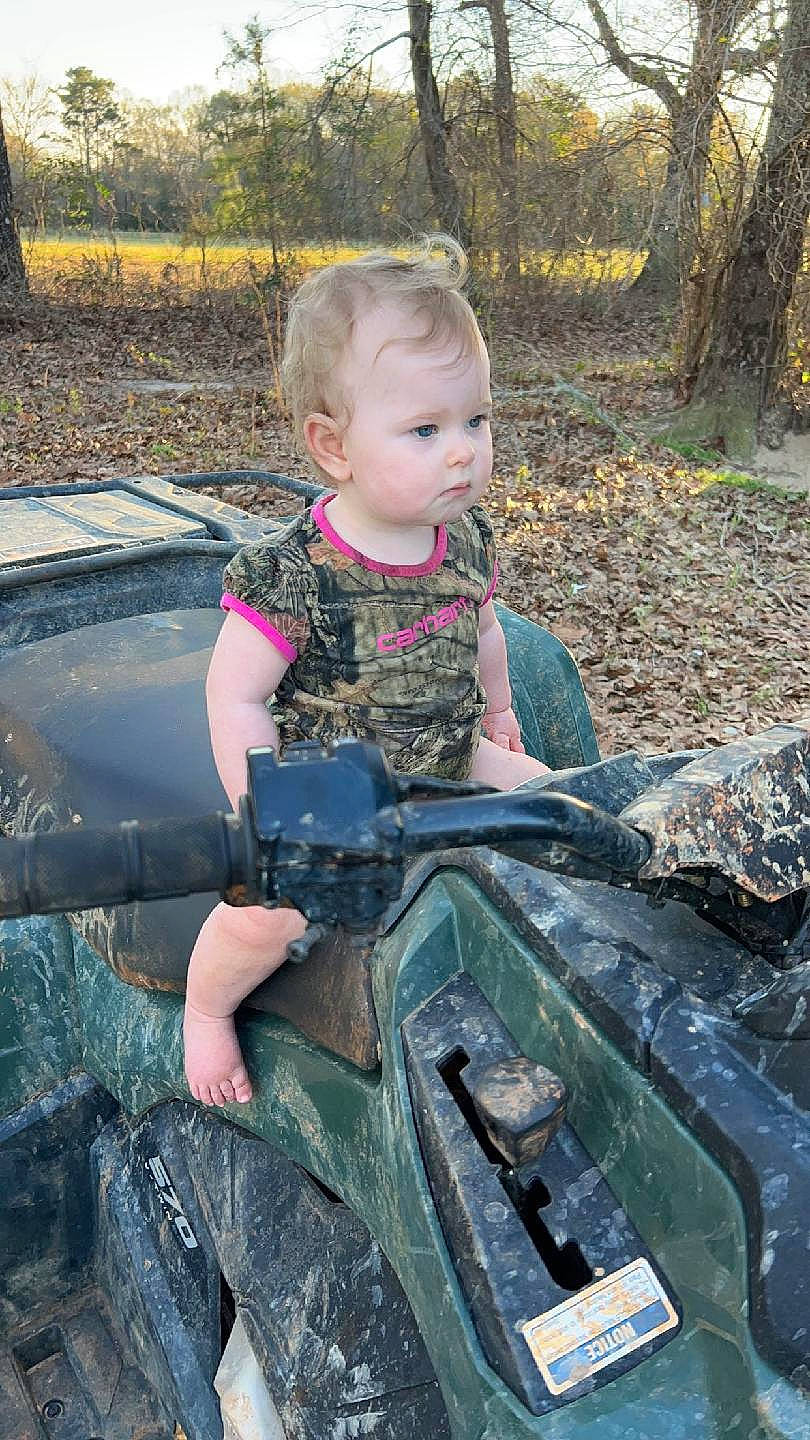 Emma joined the competition — help win amazing prizes! auto_part, automotive_exterior, automotive_tire, baby, bumper, camouflage, child, fun, grass, hood, military_camouflage, motor_vehicle, pattern, person, plant, recreation, sitting, toddler, tree, vehicle_door