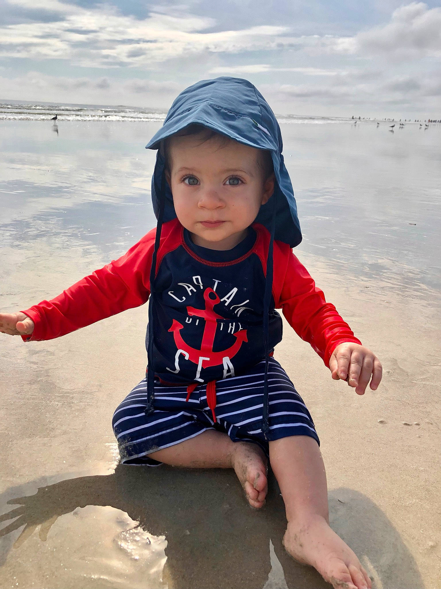 Joshua is registered to the contest to win money with this photo: baby_toddler_clothing, beach, body_of_water, cap, cloud, cool, fun, happy, hat, headwear, human_body, people_in_nature, person, photograph, sky, sleeve, standing, summer, t_shirt, toddler