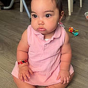 Jenna a rejoint le concours — aidez-le/la à gagner de superbes lots ! baby, child, pink_dress, sitting, indoors, floor, wooden_floor, curious, wide_eyes, hair_tuft, toy, chair, furniture, skin, person, cute, chubby, infant, casual, home