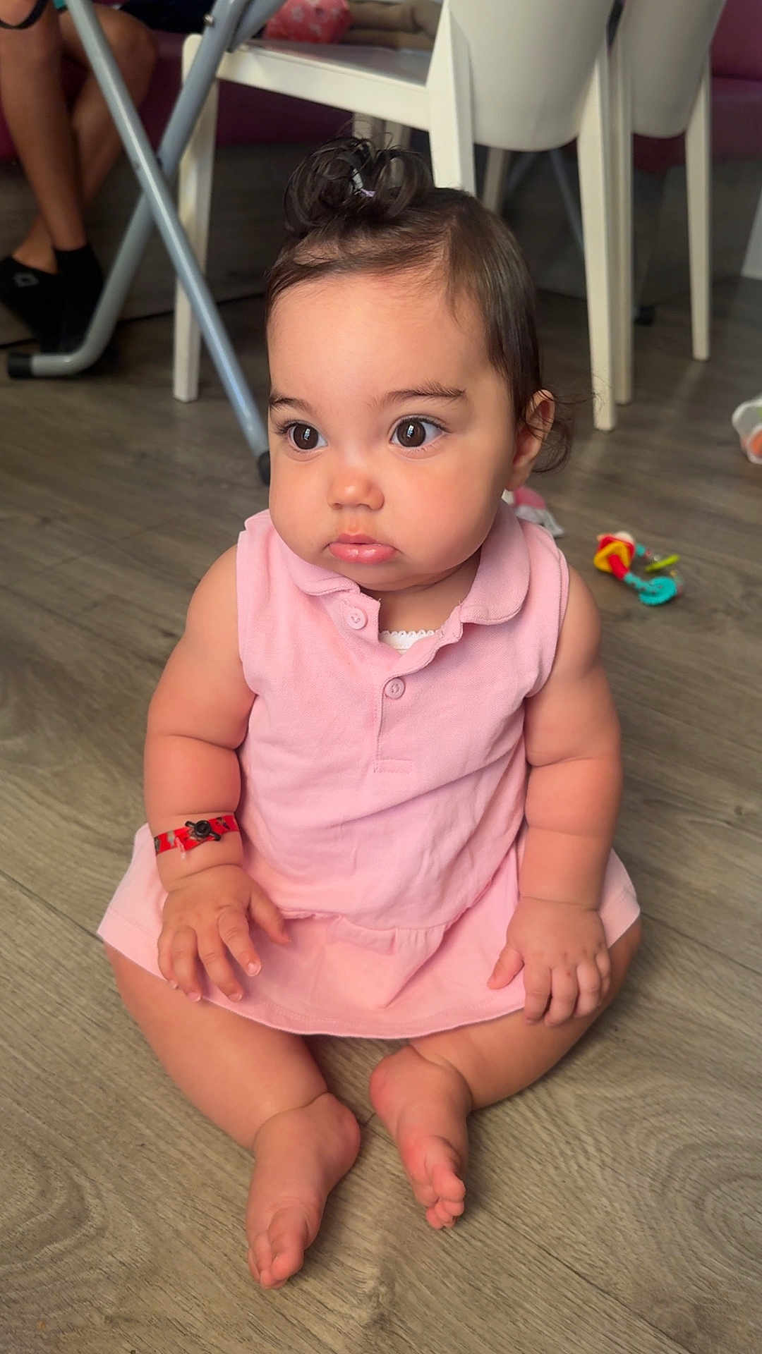 Jenna a rejoint le concours — aidez-le/la à gagner de superbes lots ! baby, child, pink_dress, sitting, indoors, floor, wooden_floor, curious, wide_eyes, hair_tuft, toy, chair, furniture, skin, person, cute, chubby, infant, casual, home