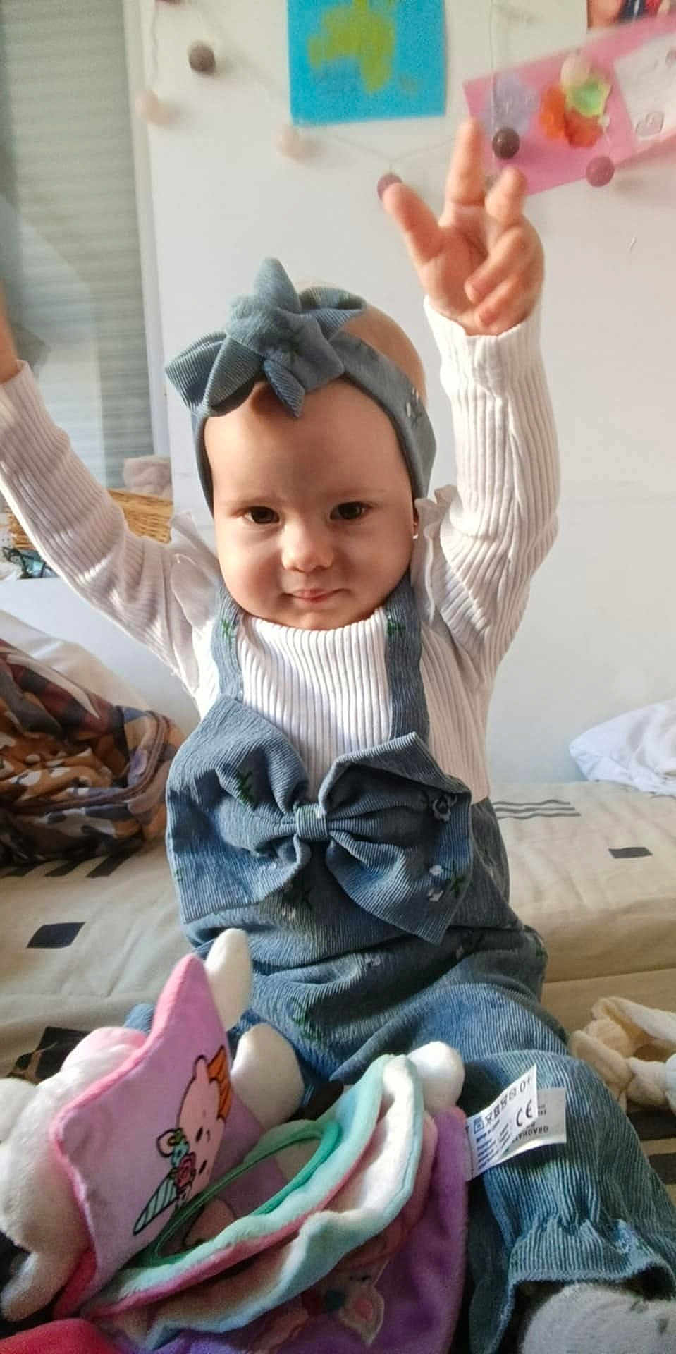Guilliana a rejoint le concours — aidez-le/la à gagner de superbes lots ! baby, child, headband, bow, denim, overalls, white_sweater, arms_up, soft_toys, bed, blanket, indoor, smiling, person, cute, infant, clothing, headwear, happy, cozy