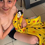 Bijou participe au concours pour gagner de l'argent avec cette photo : animal, blanket, boy, casual, cat, child, cute, floor, happy, holding, indoor, kitten, pet, pikachu, playful, sitting, smiling, tile_floor, yellow_blanket, young