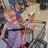 toddler, child, baby, dog, pet_store, shopping_cart, harness, purple_dress, sitting, portrait, face, eyes, ears, indoor, retail, store, pet_supplies, leash, shopping, animal