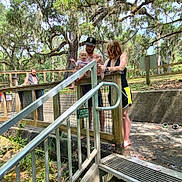 Emorie is registered to the contest to win money with this photo: baby, child, adults, family, outdoor, nature, trees, Spanish_moss, staircase, metal_steps, handrail, zoo, park, wooden_fence, baby_clothing, man, woman, standing, travel, daylight
