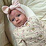 Céleste participe au concours pour gagner de l'argent avec cette photo : baby, infant, headband, bow, pink, floral, onesie, clothing, blue_eyes, face, skin, bed, blanket, soft, cute, child, newborn, portrait, indoor, cozy