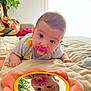 Léonie participe au concours pour gagner de l'argent avec cette photo : baby, pacifier, mirror, reflection, blue_eyes, quilt, soft_toys, indoor, curious, child, face, close_up, plant, home, colorful_blanket, person, infant, cute, portrait, laying_down