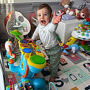 Léonie a rejoint le concours — aidez-le/la à gagner de superbes lots ! activity_center, baby, carpet, child, colorful, drum, face, happy, indoor, musical_toy, onesie, play_mat, playroom, plush_toy, reaching, smiling, standing, stuffed_animal, toddler, toys