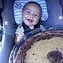 baby, car_seat, cookie_cake, smile, child, food, dessert, chocolate, happy, pillow, owl_pattern, seatbelt, cute, infant, indoor, plush, sweet, celebration, portrait, holding