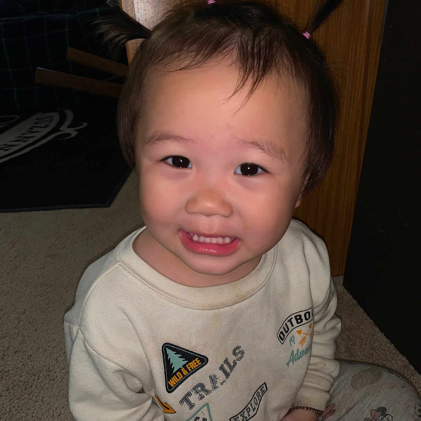 Emily is registered to the contest to win money with this photo: applique, baby, bodypart, clothing, couch, face, finger, furniture, hand, happy, head, longsleeve, pattern, person, photography, portrait, sleeve, smile, t_shirt, wood