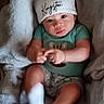 baby, infant, child, portrait, sitting, blanket, hat, beanie, clothing, green_shirt, shorts, socks, face, eyes, hands, fingers, cozy, indoor, cuddly, photography