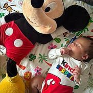 Ibrahim is registered to the contest to win money with this photo: baby, sleeping, plush_toy, mickey_mouse, onesie, colorful, blanket, animal_print, child, cute, soft_toy, indoor, infant, peaceful, resting, toddler, toy, person, bedroom, cozy
